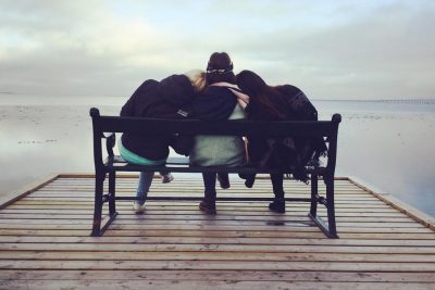 Three women sitting close on bench